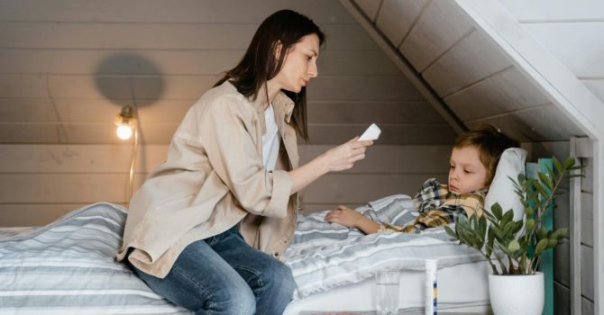 Ibu mengukur suhu tubuh anak yang demam sebagai deteksi awal influenza A